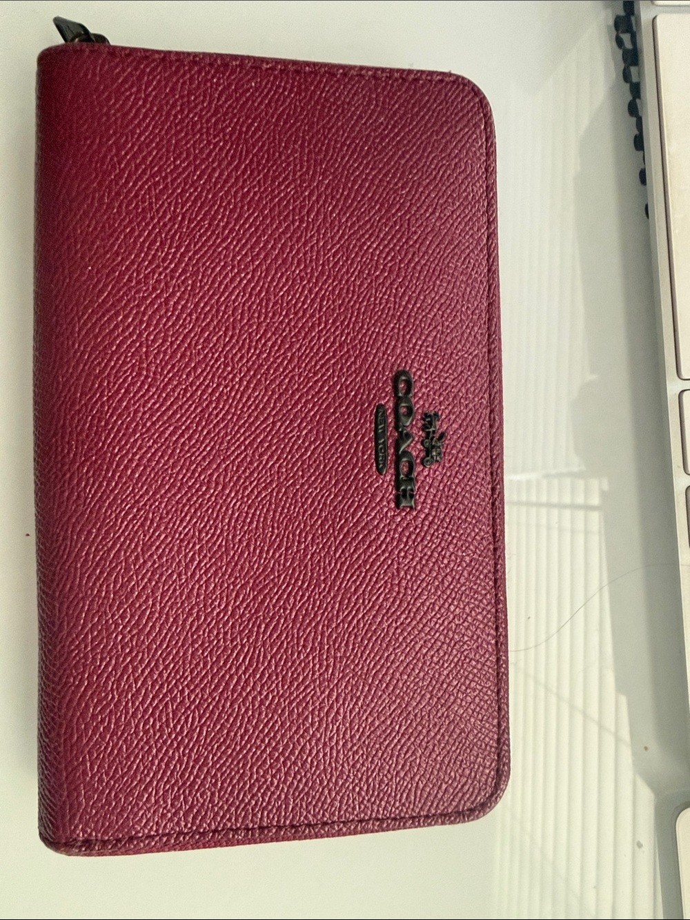 Coach Zip-Around Leather Phone Wallet in pink burgundy, saffiano textured.